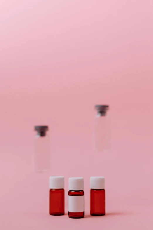three vials filled with blood on a pink background, a picture, by Jacob Toorenvliet, pexels, rinko kawauchi, thumbnail, formulas, concert