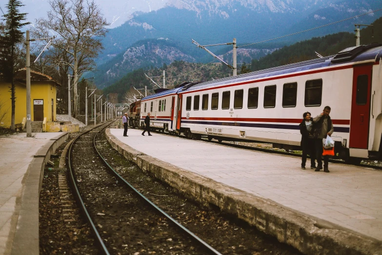 a group of people standing on a platform next to a train, by Lucia Peka, pexels contest winner, bosnian, mountains, 🚿🗝📝