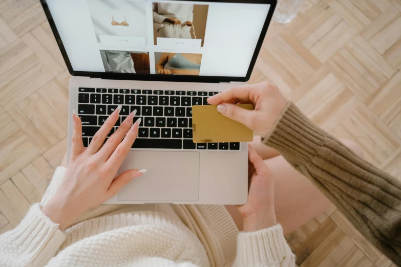 a woman sitting on the floor using a laptop computer, trending on pexels, holding ace card, beige and gold tones, at checkout, thumbnail