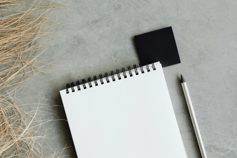 a notepad sitting on top of a table next to a pen, trending on pexels, visual art, square shapes, white and black, background image