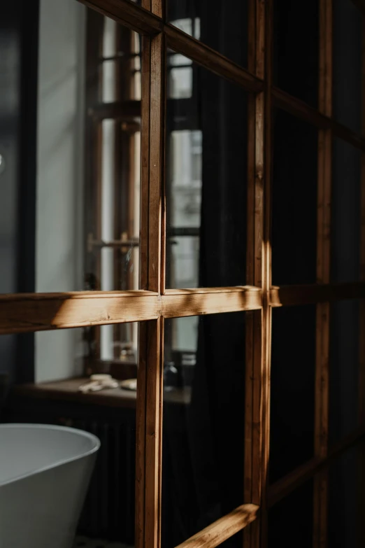 a white bath tub sitting in a bathroom next to a window, a picture, by Jan Tengnagel, unsplash, light and space, black vertical slatted timber, cell bars, brown, close up to the screen