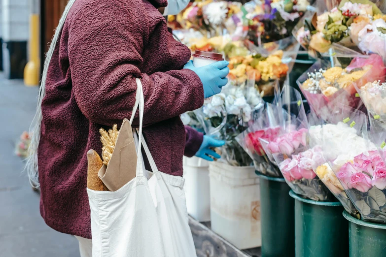 a woman standing in front of a bunch of flowers, by Carey Morris, pexels, getting groceries, starving artist wearing overalls, market stalls, thumbnail