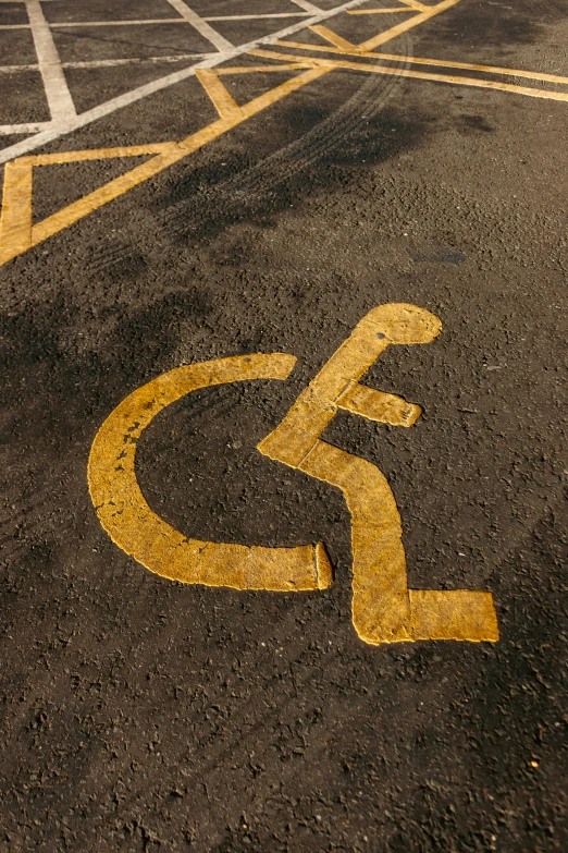 a parking lot with a handicap sign painted on it, trending on pexels, graffiti, in scotland, yellow, square, lane brown