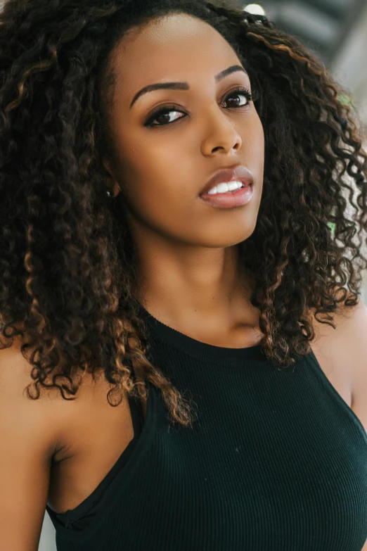 a woman with curly hair wearing a black top, trending on pexels, light-brown skin, sydney sweeney, bay area, liberty curls