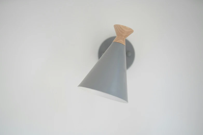 a close up of a light on a wall, by Niels Lergaard, pointy conical hat, gray color, on wood, the jetsons