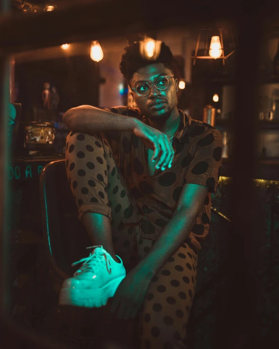 a woman sitting on a chair in a dimly lit room, trending on pexels, afrofuturism, mid-shot of a hunky, 2 1 savage, sitting at a bar, androgynous male