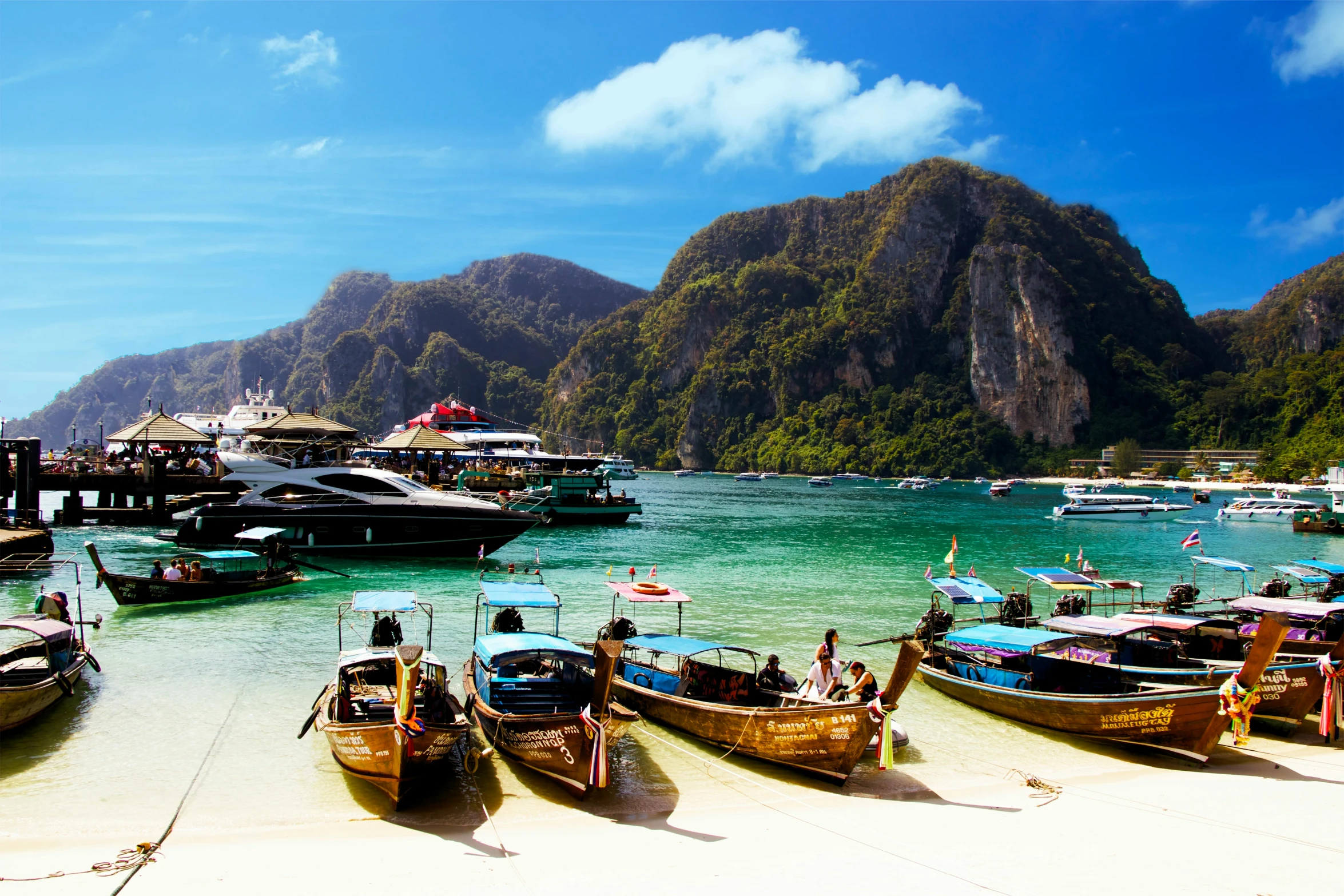 a group of boats sitting on top of a sandy beach, thai architecture, crystal clear blue water, multicoloured, black