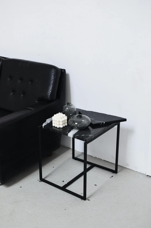 a black couch sitting in a living room next to a table, unsplash, minimalism, made of liquid metal and marble, square, low quality photo, hyperrealistic n- 4