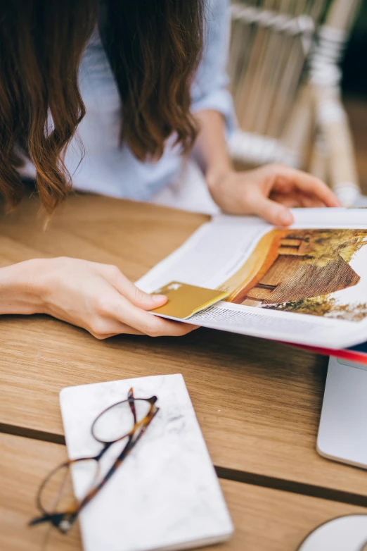 a woman sitting at a table reading a book, a picture, pexels contest winner, brochure, gold encrustations, college, national geographics