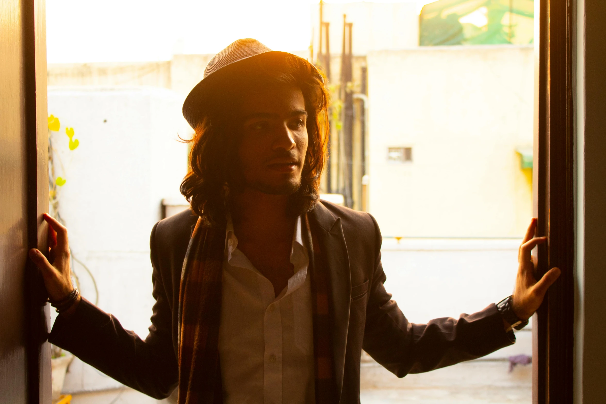 a man that is standing in front of a door, an album cover, unsplash, renaissance, avan jogia angel, a suited man in a hat, sun flare, taken in the late 2010s
