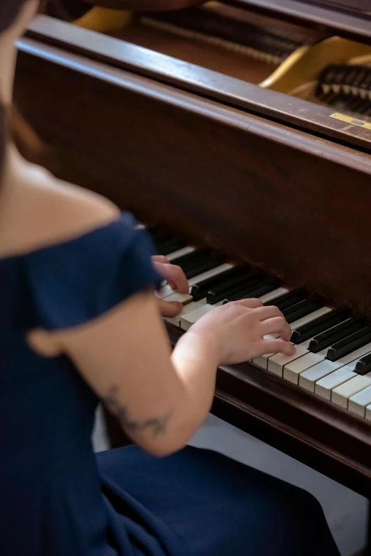a woman in a blue dress playing a piano, by Arabella Rankin, trending on unsplash, tattooed, paul barson, documentary still, sydney hanson
