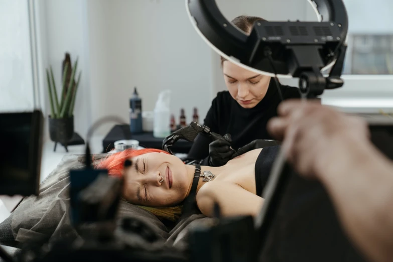 a woman getting her hair done by a hair stylist, a tattoo, by Lee Loughridge, trending on pexels, hyperrealism, she is laying on her back, lachlan bailey, shot with canon eoa 6 d mark ii, akali