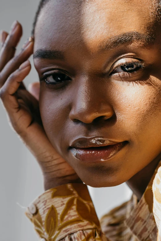 a close up of a person wearing a shirt, a portrait, by Lily Delissa Joseph, trending on unsplash, brown skin. light makeup, yellow hue, smooth healthy skin, smooth in _ the background