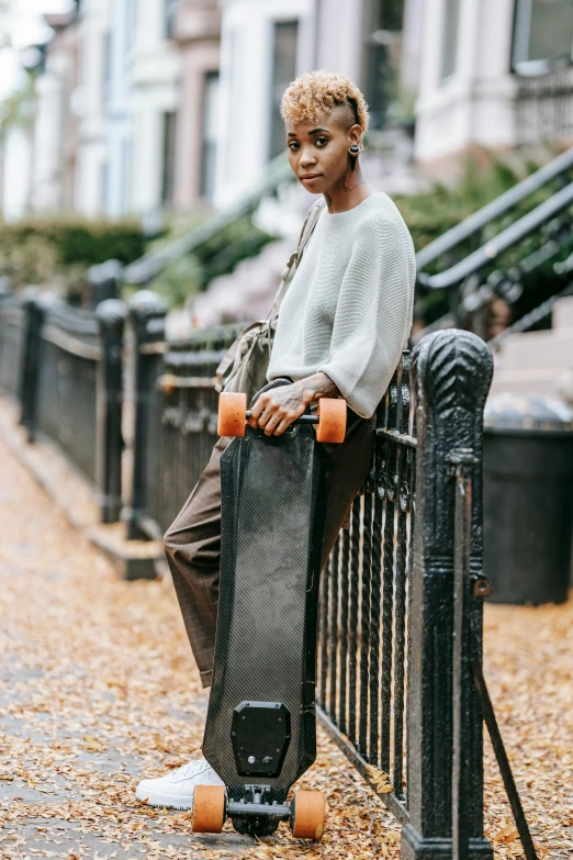 a woman sitting on a fence with a skateboard, by Thomas Fogarty, trending on pexels, adut akech, wearing casual sweater, nyc, ashteroth