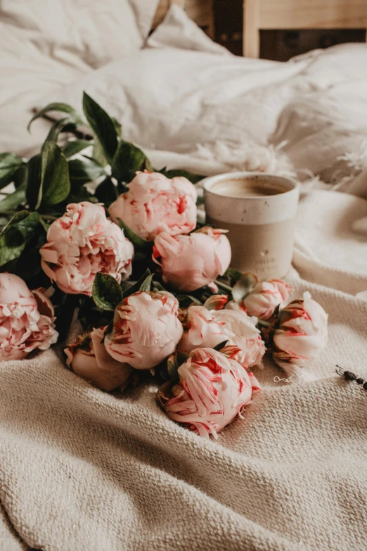 a bouquet of pink flowers sitting on top of a bed, a still life, pexels contest winner, romanticism, morning coffee, peonies, cream, soft muted colors