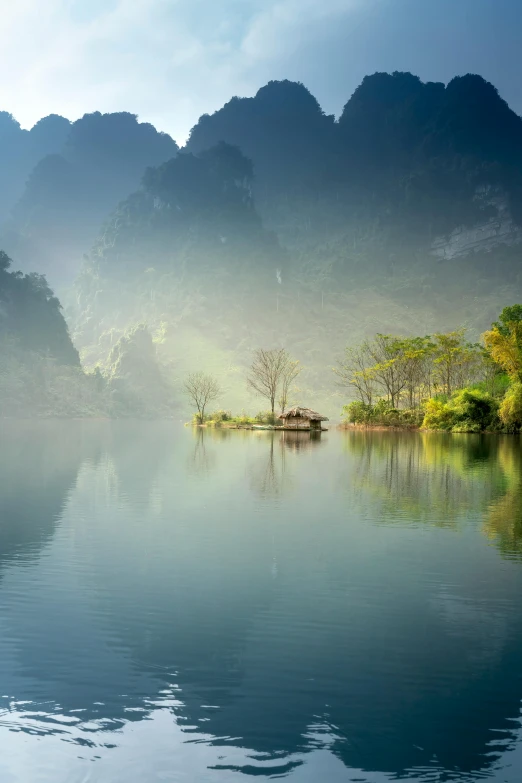 a body of water with mountains in the background, inspired by Li Keran, vietnam, soft light misty, paul barson, chinese village