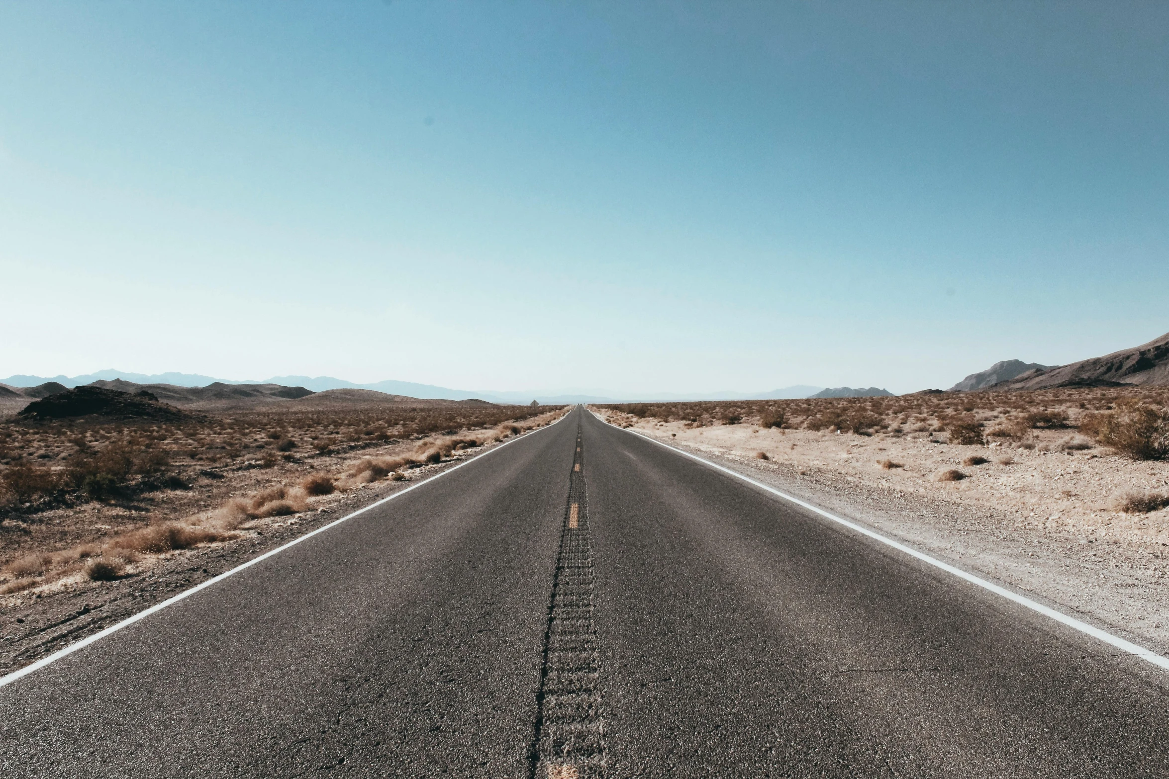 an empty road in the middle of the desert, by Ryan Pancoast, trending on unsplash, visual art, cloudless blue sky, thumbnail, background image