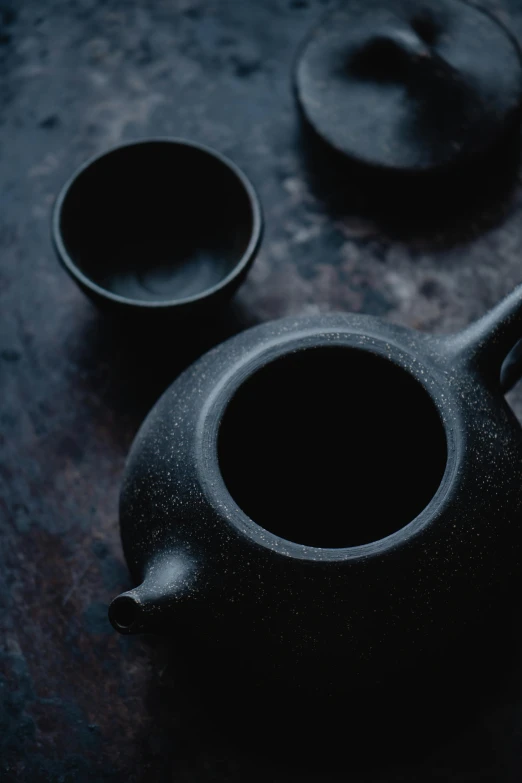 a black teapot sitting on top of a wooden table, inspired by Sesshū Tōyō, trending on unsplash, cups and balls, texture detail, (night), made of tar