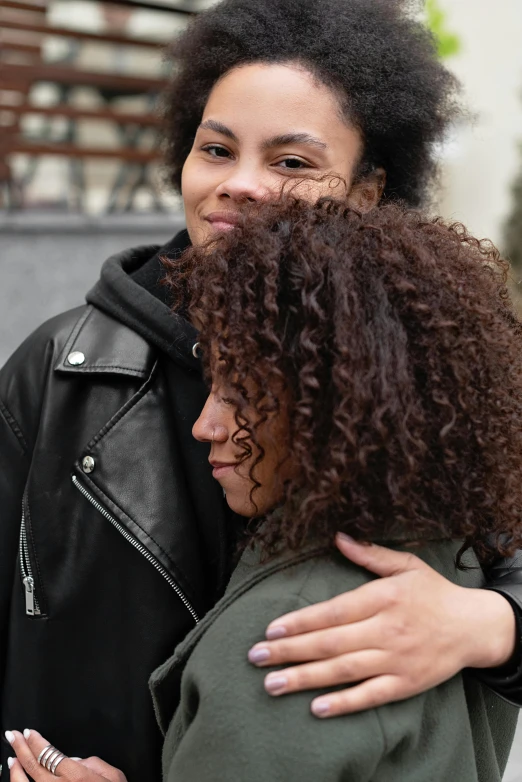 a couple of women standing next to each other, trending on pexels, renaissance, east african man with curly hair, hugs, black haired girl wearing hoodie, curly brown hair