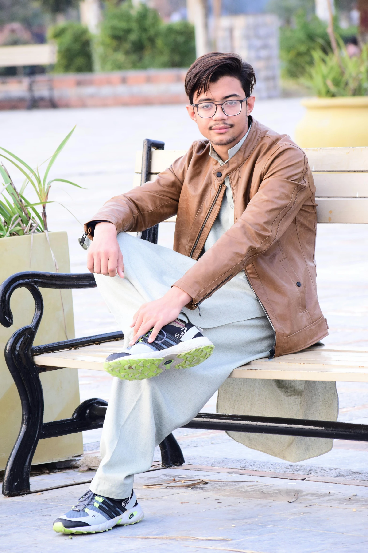 a man sitting on top of a wooden bench, a picture, inspired by Saurabh Jethani, wearing a brown leather coat, full body and head shot, student, greenish tinge