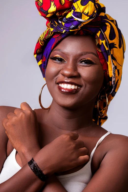 a smiling woman with a colorful turban on her head, an album cover, by Chinwe Chukwuogo-Roy, pexels contest winner, adut akech, casual pose, smiling :: attractive, low iso