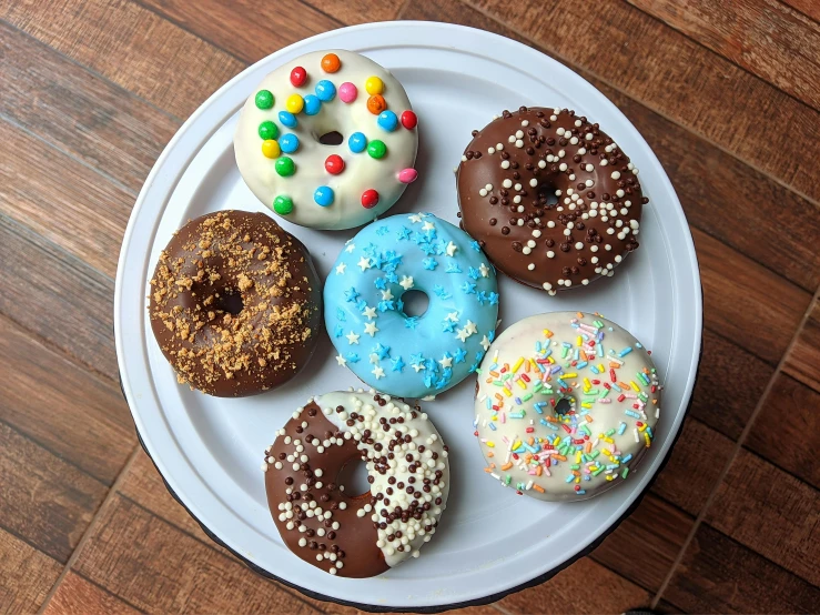 a white plate topped with donuts covered in sprinkles, 🦩🪐🐞👩🏻🦳, various colors, thumbnail, chocolate