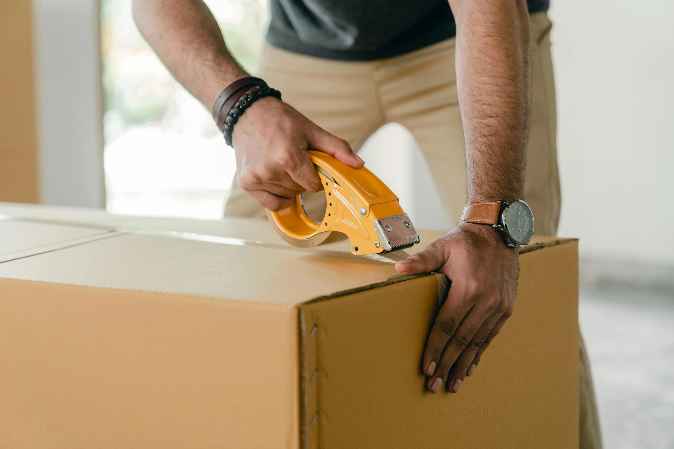 a man holding a stapler on top of a cardboard box, by Carey Morris, pexels contest winner, hurufiyya, avatar image, 40mm tape, brown, gold