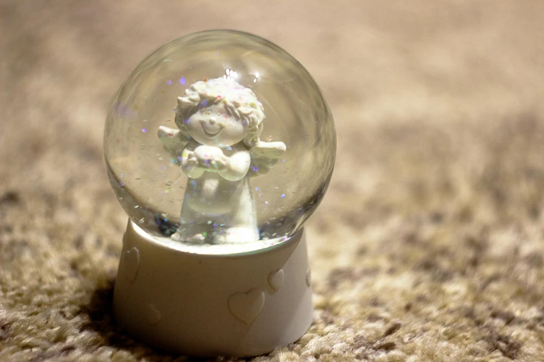 a snow globe with a little angel inside of it, a marble sculpture, inspired by Raymond Briggs, 35 mm product photo”, mood light, bubbly, cherub