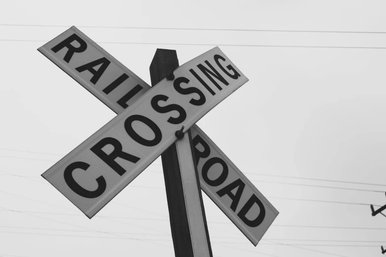 a black and white photo of a railroad crossing sign, by Carey Morris, unsplash, square, [ realistic photography ], crosses, gray