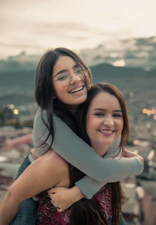 two women hugging each other on top of a building, trending on unsplash, quito school, portrait shot 8 k, square, teen, screensaver