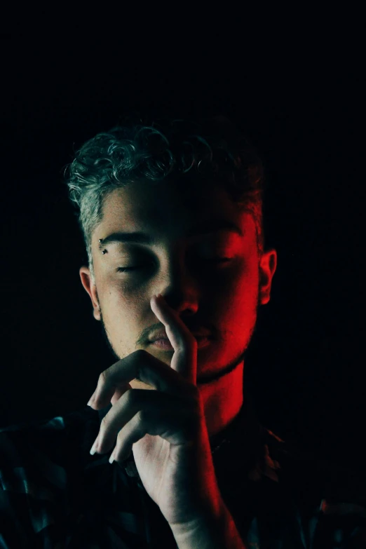 a man smoking a cigarette in the dark, an album cover, inspired by Elsa Bleda, trending on pexels, zayn malik, with index finger, androgynous person, highly reflective