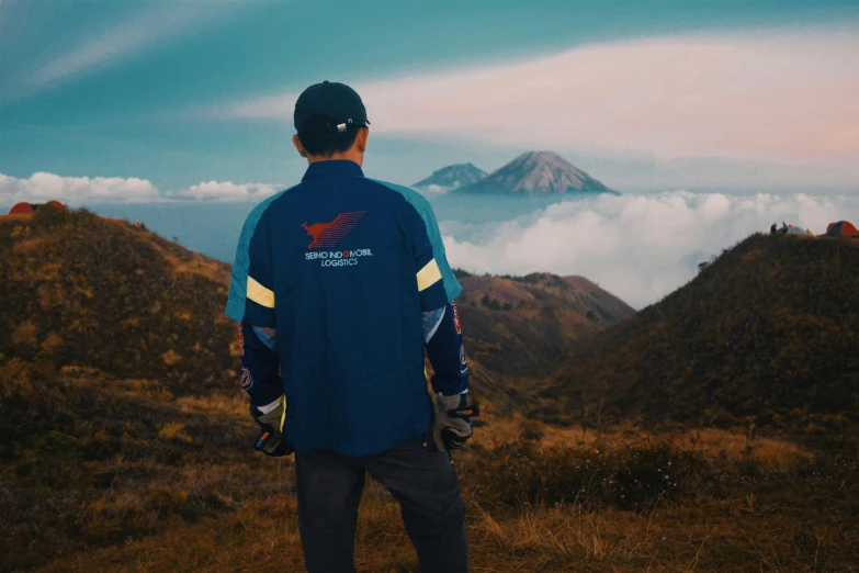a man standing on top of a mountain, inspired by Rudy Siswanto, unsplash contest winner, sumatraism, wearing blue jacket, back view, avatar image, pteranadon styling