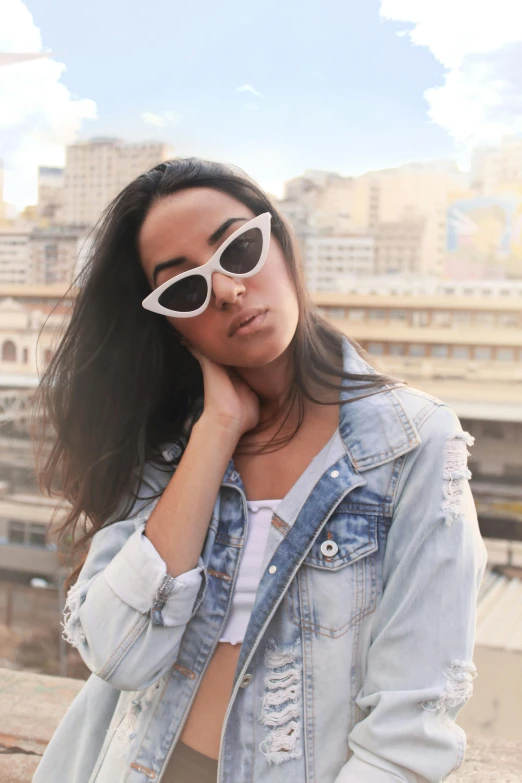 a woman standing on top of a roof next to a building, by Robbie Trevino, trending on pexels, photorealism, fashion model in sunglasses, egypt, wearing a jeans jackets, portrait of ana de armas