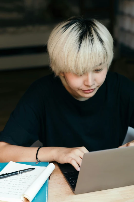 a woman sitting at a table using a laptop computer, by Jang Seung-eop, trending on pexels, short platinum hair tomboy, teenage boy, ethnicity : japanese, reading