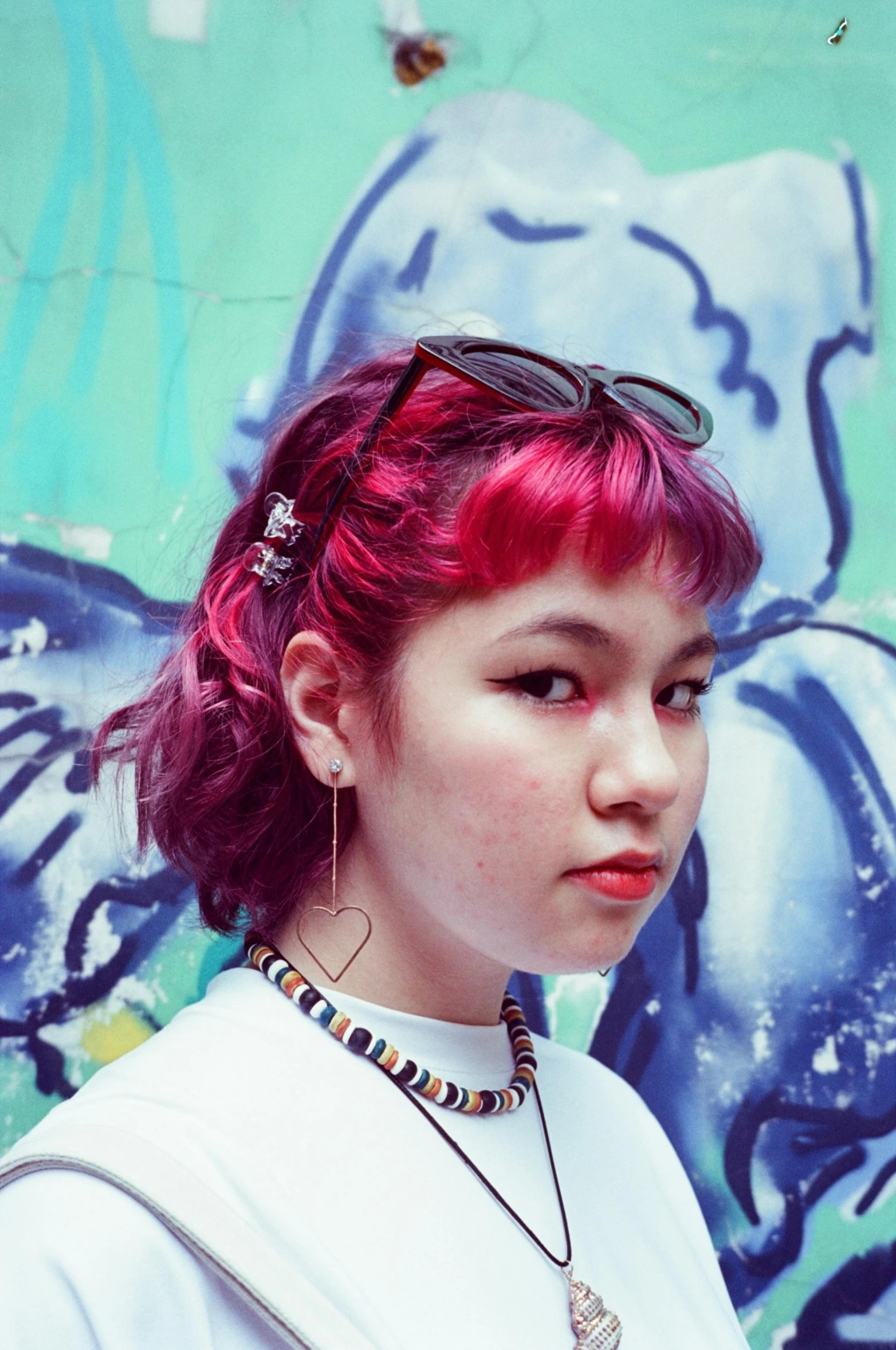 a woman with red hair standing in front of a wall, an album cover, inspired by Yuko Tatsushima, trending on pexels, headshot profile picture, colorful pigtail, heavy grainy picture, currents