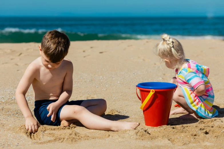 two children playing in the sand at the beach, by Arabella Rankin, pexels contest winner, teaser, in a sunny day, thumbnail, 1 4 9 3