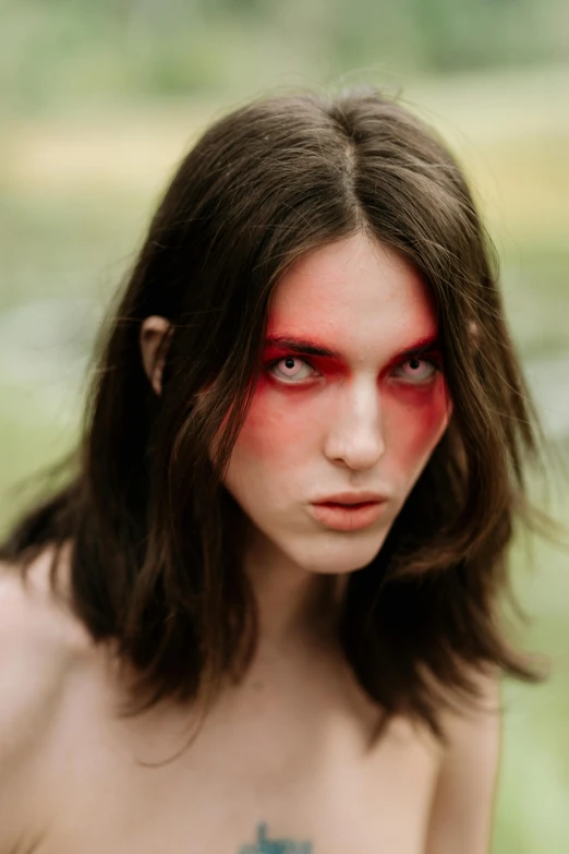 a woman with blood painted on her face, an album cover, inspired by Elsa Bleda, trending on pexels, renaissance, beautiful androgynous girl, red eye, brunette woman, red grass