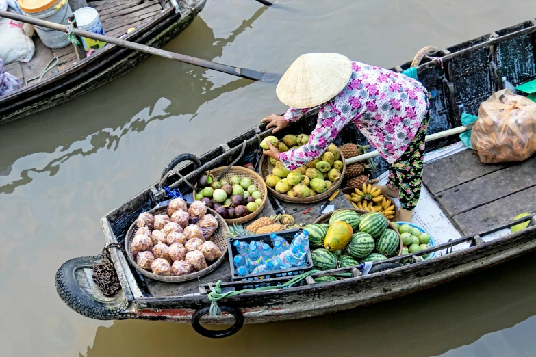 a person in a boat filled with fruits and vegetables, bao phan, boats in the water