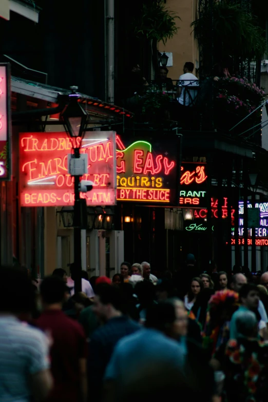 a crowd of people walking down a street next to tall buildings, pexels, renaissance, dimly lit dive bar, new orleans, colorful signs, promo image