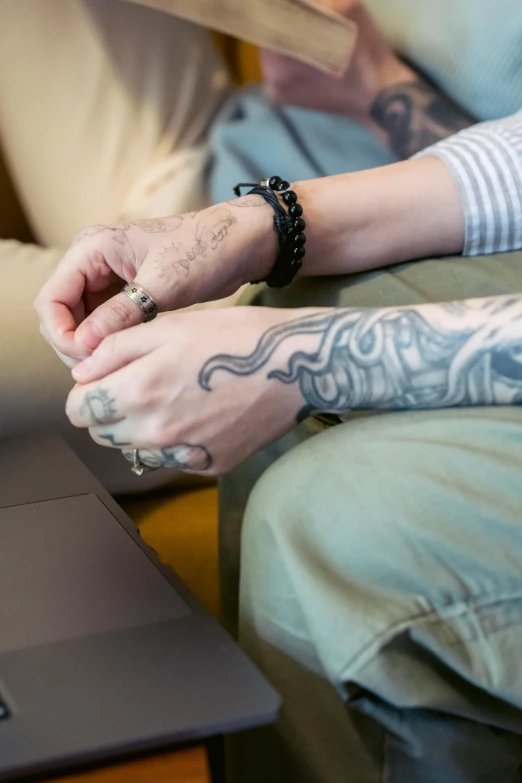 a close up of a person sitting on a couch with a laptop, a tattoo, holding each other hands, supportive, lesbians, slide show