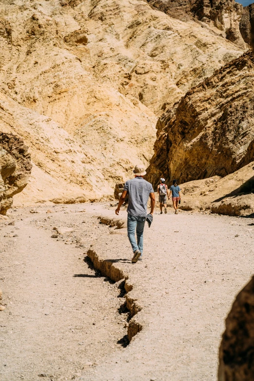 a group of people walking down a dirt road, les nabis, inside a gorge, death valley, multiple stories, unsplash photography