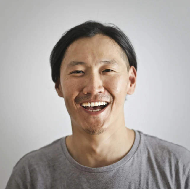 a man with a smile on his face, a character portrait, inspired by Joong Keun Lee, unsplash, on grey background, david choe, smileing nright, small chin