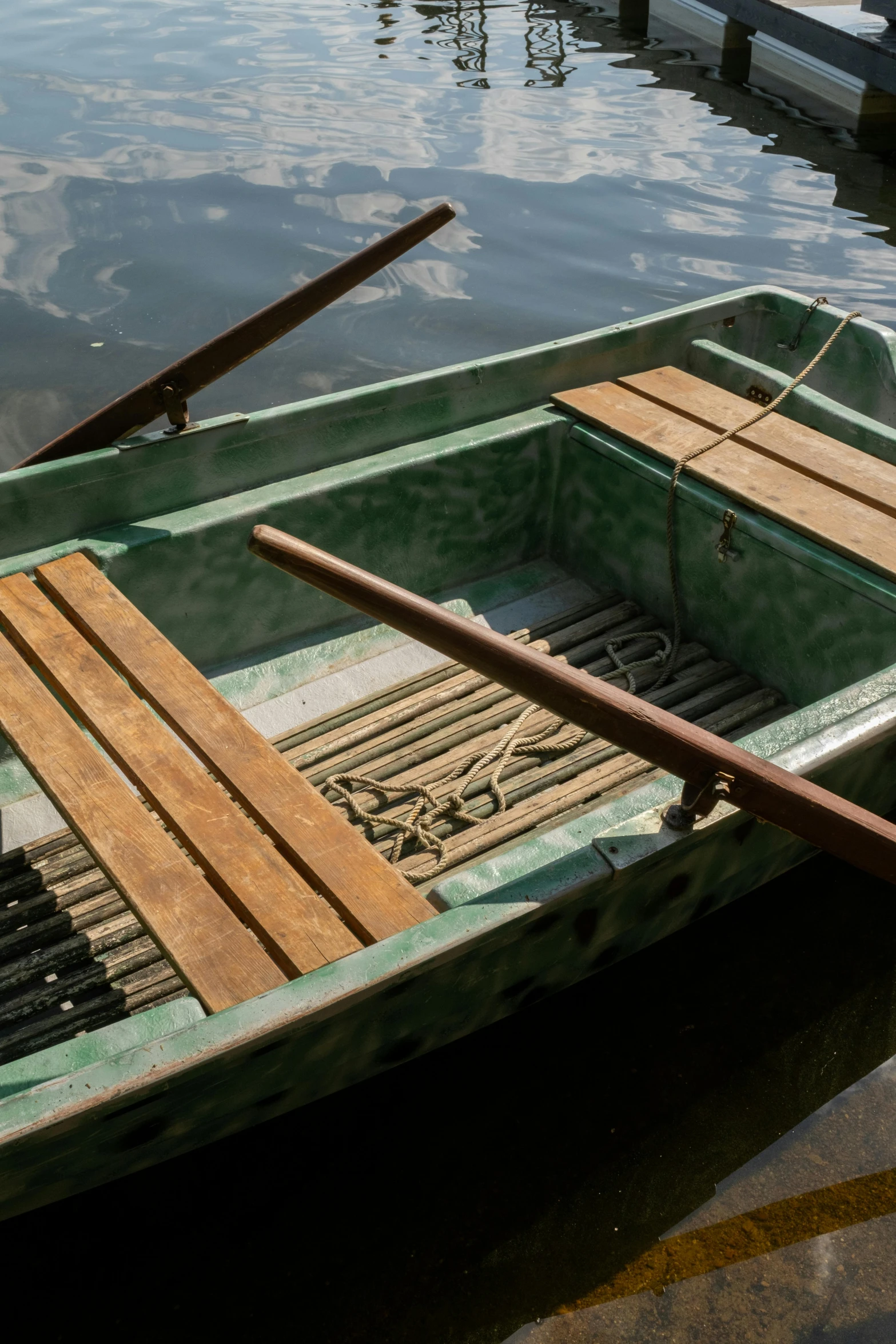 a row boat sitting on top of a lake next to a dock, up close, in style of ruan jia, straight neck, dingy