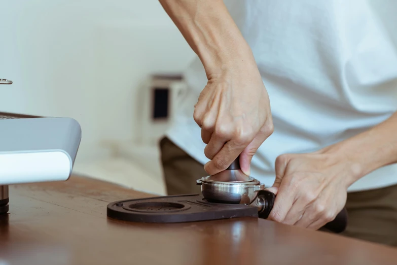 a close up of a person pressing a button on a stove, a still life, unsplash, process art, tea ceremony scene, aussie baristas, sitting on a mocha-colored table, metal lid