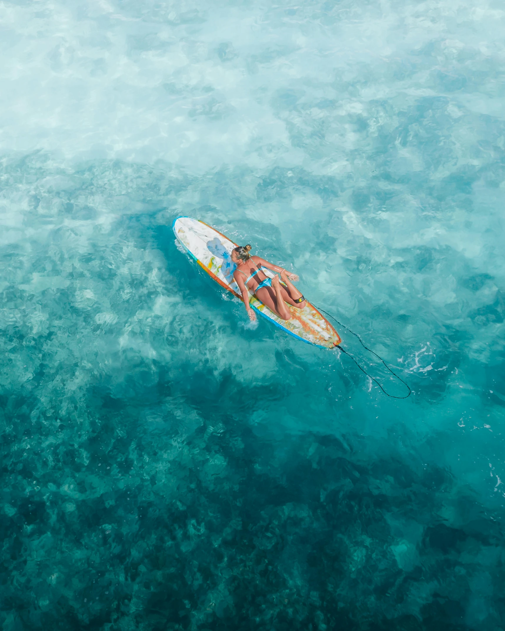 a person riding a surfboard on top of a body of water, from above