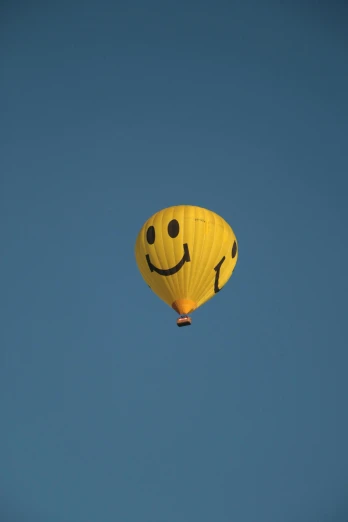 a yellow hot air balloon with a smiley face on it, by Attila Meszlenyi, pexels contest winner, sky blue, 15081959 21121991 01012000 4k, zoomed out view, shot on sony a 7