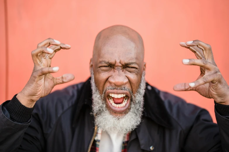 a man making a funny face with his hands, by Will Ellis, pexels contest winner, black arts movement, long white beard, ray lewis yelling, angry looking at camera, album photo