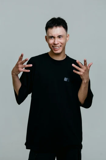 a man that is standing up with his hands in the air, an album cover, inspired by Ding Guanpeng, unsplash, realism, wearing a black shirt, sarcastic smile showing teeth, in a photo studio, male teenager
