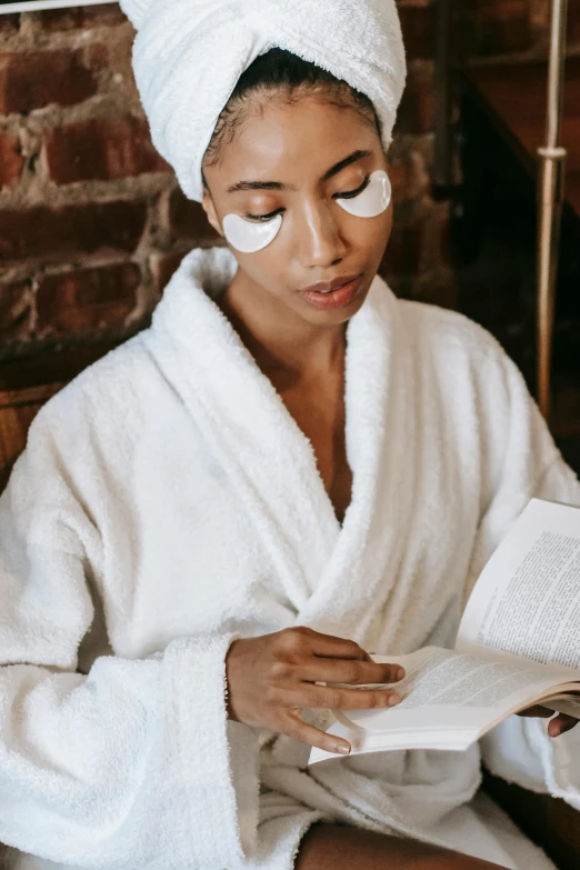 a woman in a bathrobe reading a book, trending on pexels, black eye mask, wearing white cloths, skincare, reading for a party