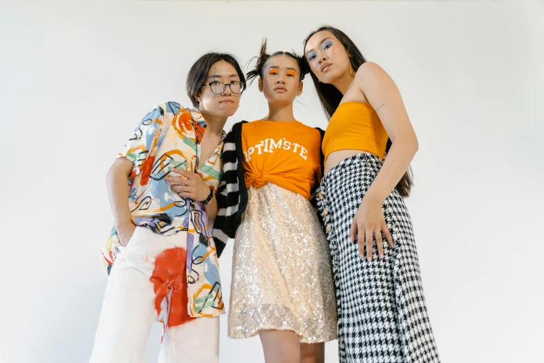 a group of three women standing next to each other, trending on pexels, aestheticism, orange and white, asian descent, fashion design, queer woman